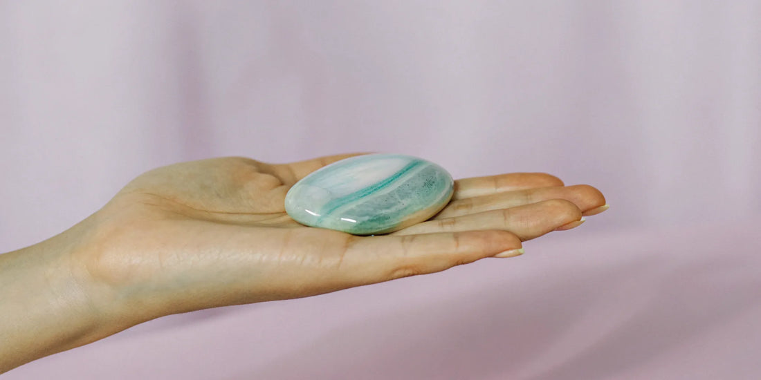 Thumb worry stone held between thumb and forefinger for anxiety relief.