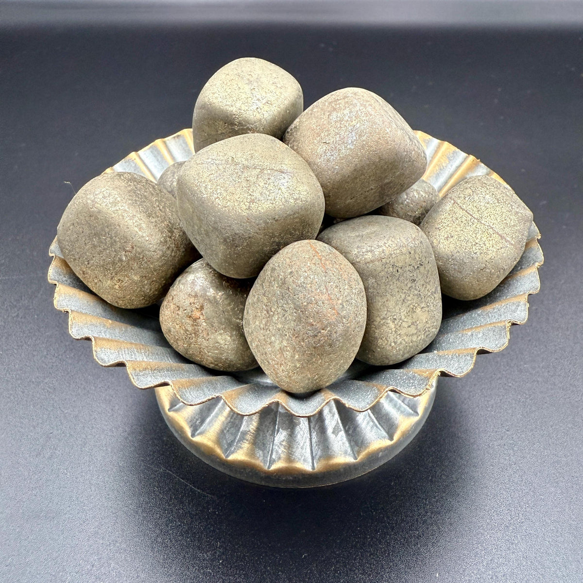 Pyrite tumbled stones in a small brass dish