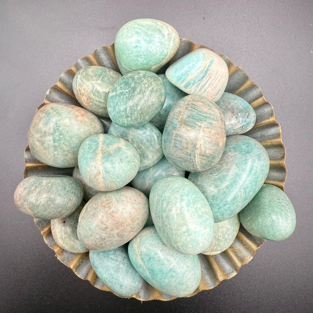 Sea-green amazonite tumbled stones in a small brass dish