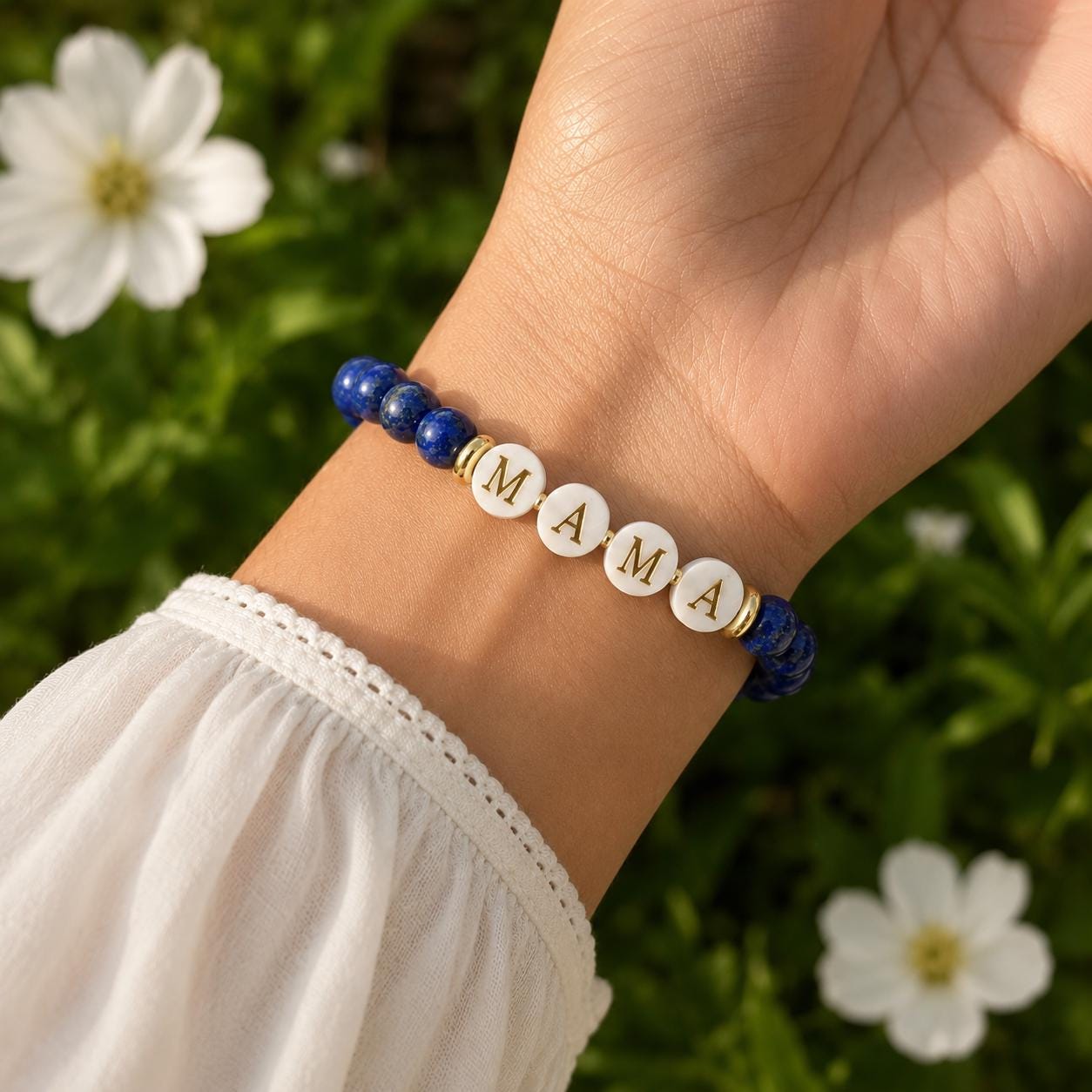May include: A beaded bracelet featuring deep blue lapis lazuli stones and four white circular beads with gold lettering that spells out the word MAMA, accented by small gold-toned spacers between the beads and the lettered components.