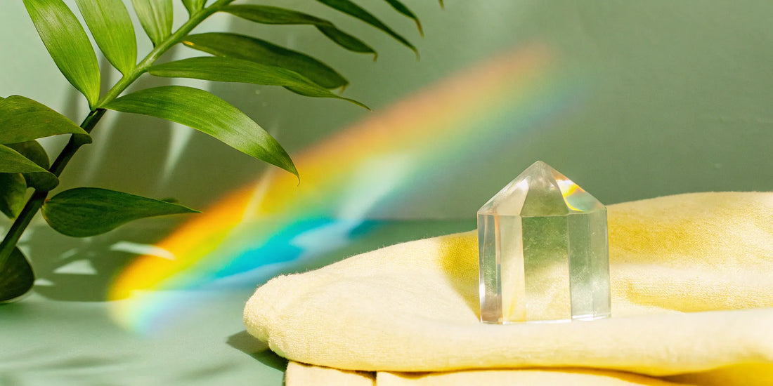 Clear quartz crystal on yellow cloth with rainbow light.