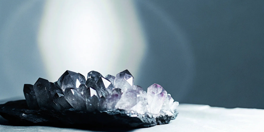 Amethyst crystal cluster with dark base and purple crystals.