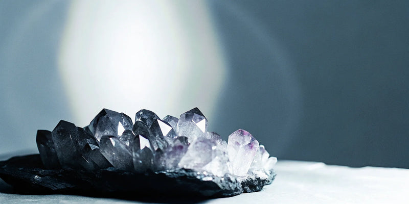 Amethyst crystal cluster with dark base and purple crystals.