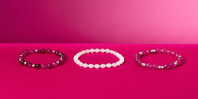 Healing crystal bracelets on a pink background.
