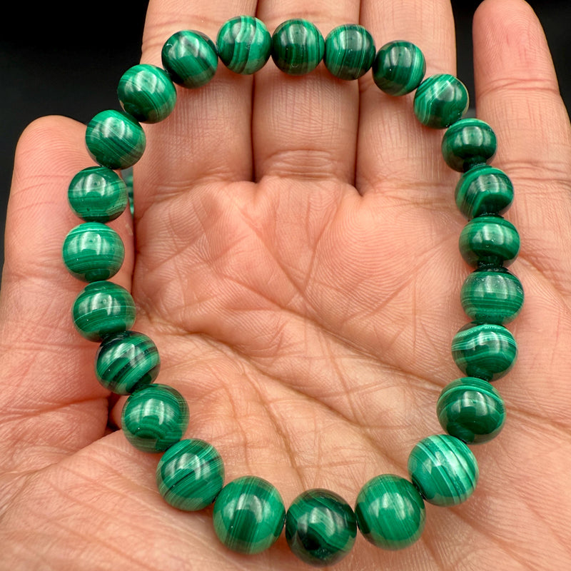 Banded green malachite beaded bracelet held in an open palm