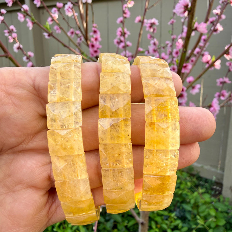 Faceted citrine bracelets held in the hand in warm natural daylight