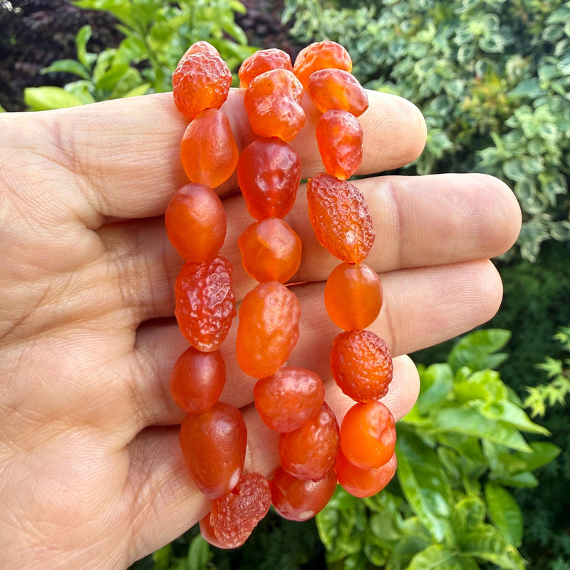 Natural carnelian bracelet held in hand — carnelian is traditionally associated with courage, motivation and steady confidence
