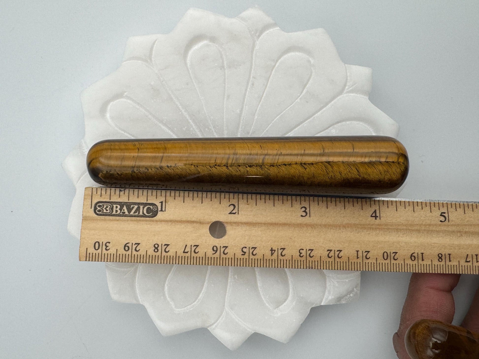 Wooden tool on a white cloth with a ruler for scale on a gray background