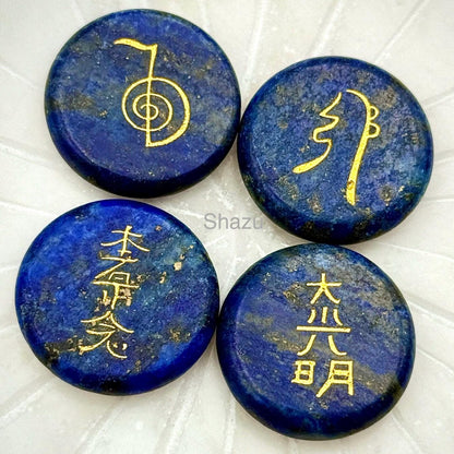May include: Four round, deep blue lapis lazuli stones with gold-colored symbols and characters. The stones have a polished surface and varying patterns. The image includes the word "Shazu".