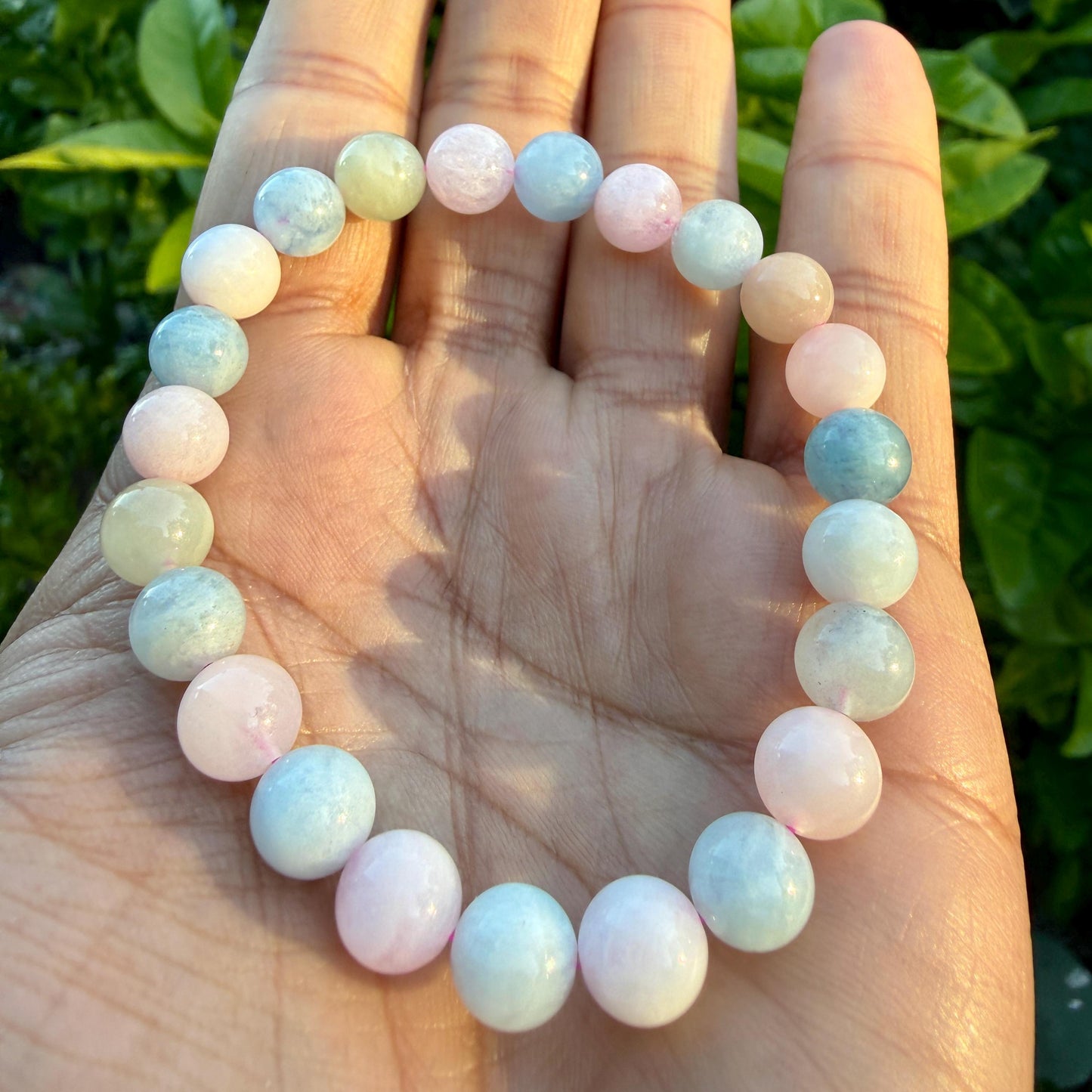 May include: A stretch bracelet composed of smooth, round beads in alternating shades of pale pink, soft blue, and creamy white. The beads are polished and uniform in size, arranged in a continuous circular pattern to form a flexible wrist accessory.