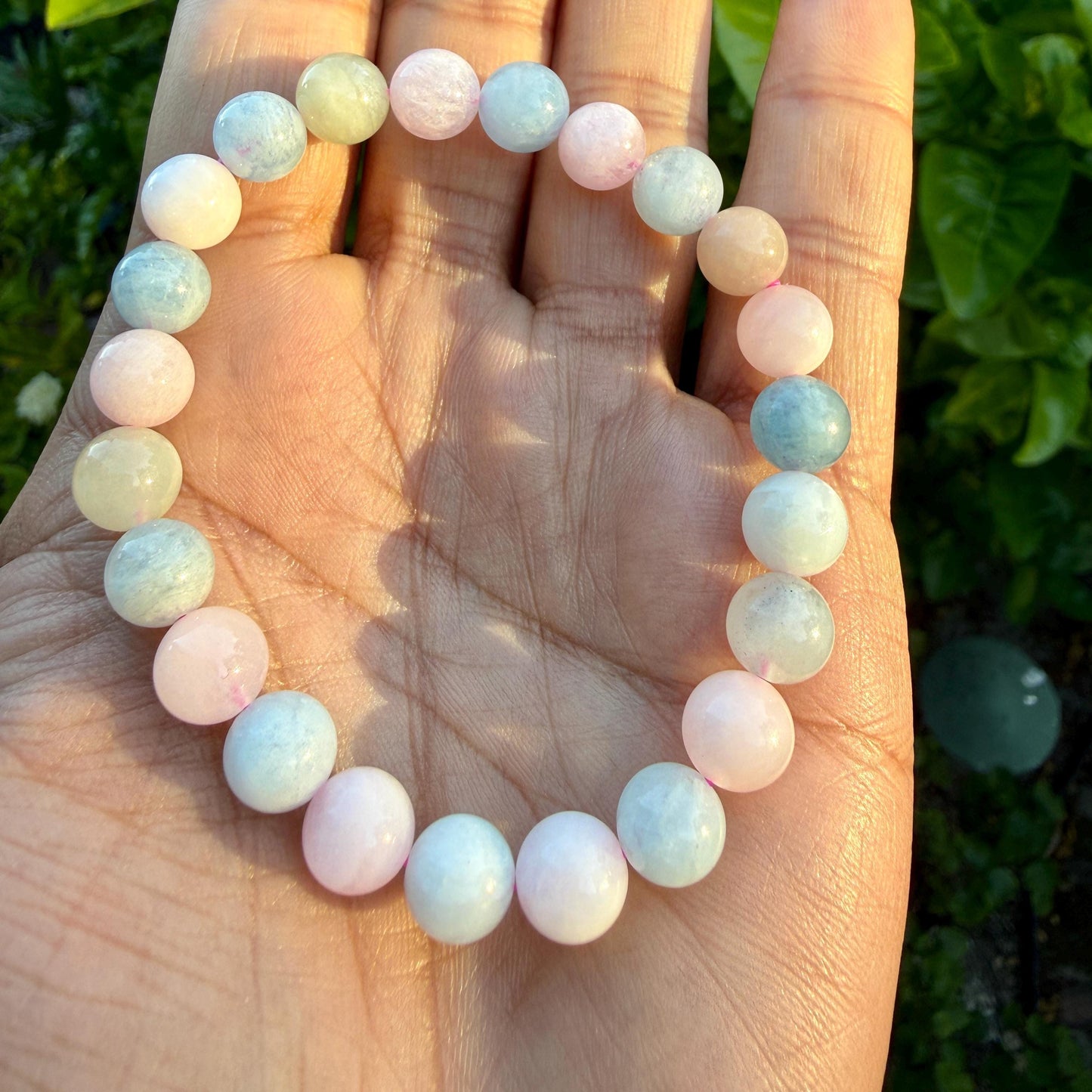 May include: A stretch bracelet composed of smooth, round beads in alternating shades of pale pink, soft blue, and creamy off-white. The beads are strung together in a circular pattern, creating a continuous loop of pastel-colored stones.