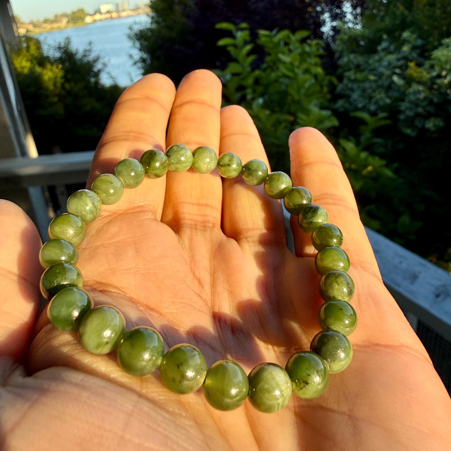 May include: A stretch bracelet composed of smooth, round, translucent olive green beads. The beads exhibit natural variations in color and internal texture, ranging from light to deep mossy green tones, strung together in a circular formation.