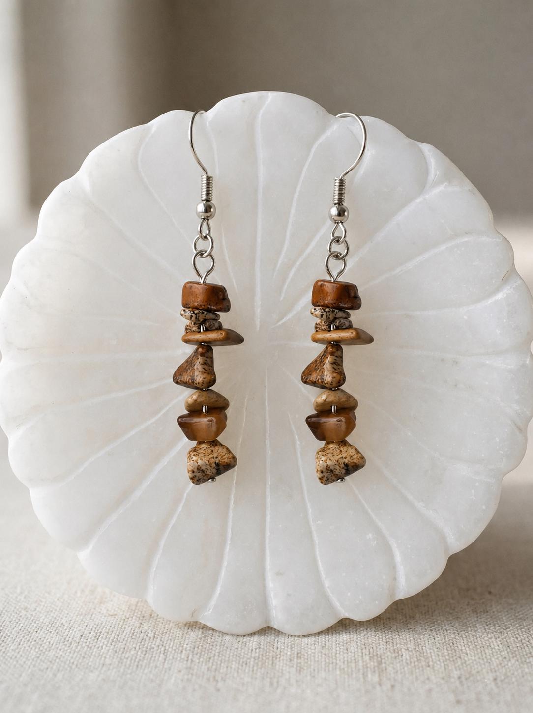 May include: A pair of dangle earrings featuring a vertical arrangement of five irregular, tumbled brown and tan jasper stone chips. The stones are strung on a thin silver-toned metal wire, finished with a standard silver-toned metal fishhook ear wire.