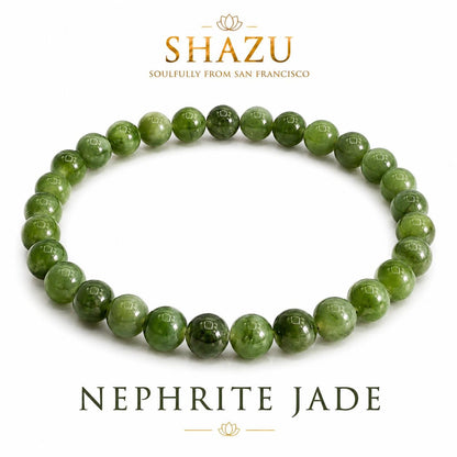 May include: A circular bracelet composed of smooth, polished, round green nephrite jade beads. The text SHAZU SOULFULLY FROM SAN FRANCISCO appears above the bracelet, and the text NEPHRITE JADE is printed in a serif font below the jewelry piece.