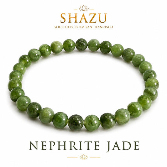 May include: A circular bracelet composed of smooth, polished, round green nephrite jade beads. The text SHAZU SOULFULLY FROM SAN FRANCISCO appears above the bracelet, and the text NEPHRITE JADE is printed in a serif font below the jewelry piece.