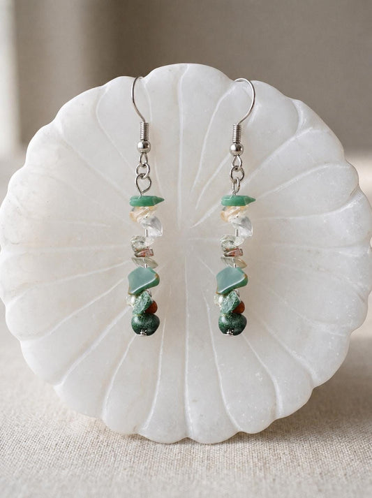 May include: A pair of dangle earrings featuring silver-toned metal hooks and a vertical arrangement of small, irregular, tumbled gemstone chips in shades of green, clear, and brown, suspended in a linear design from the top metal loop.