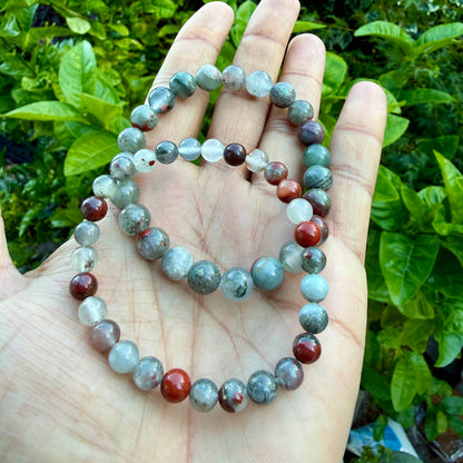 May include: Two elastic bracelets composed of round, polished gemstone beads. The beads feature a mix of translucent light gray, cloudy white, and opaque deep red colors, with some beads displaying speckled or marbled patterns throughout the surfaces.