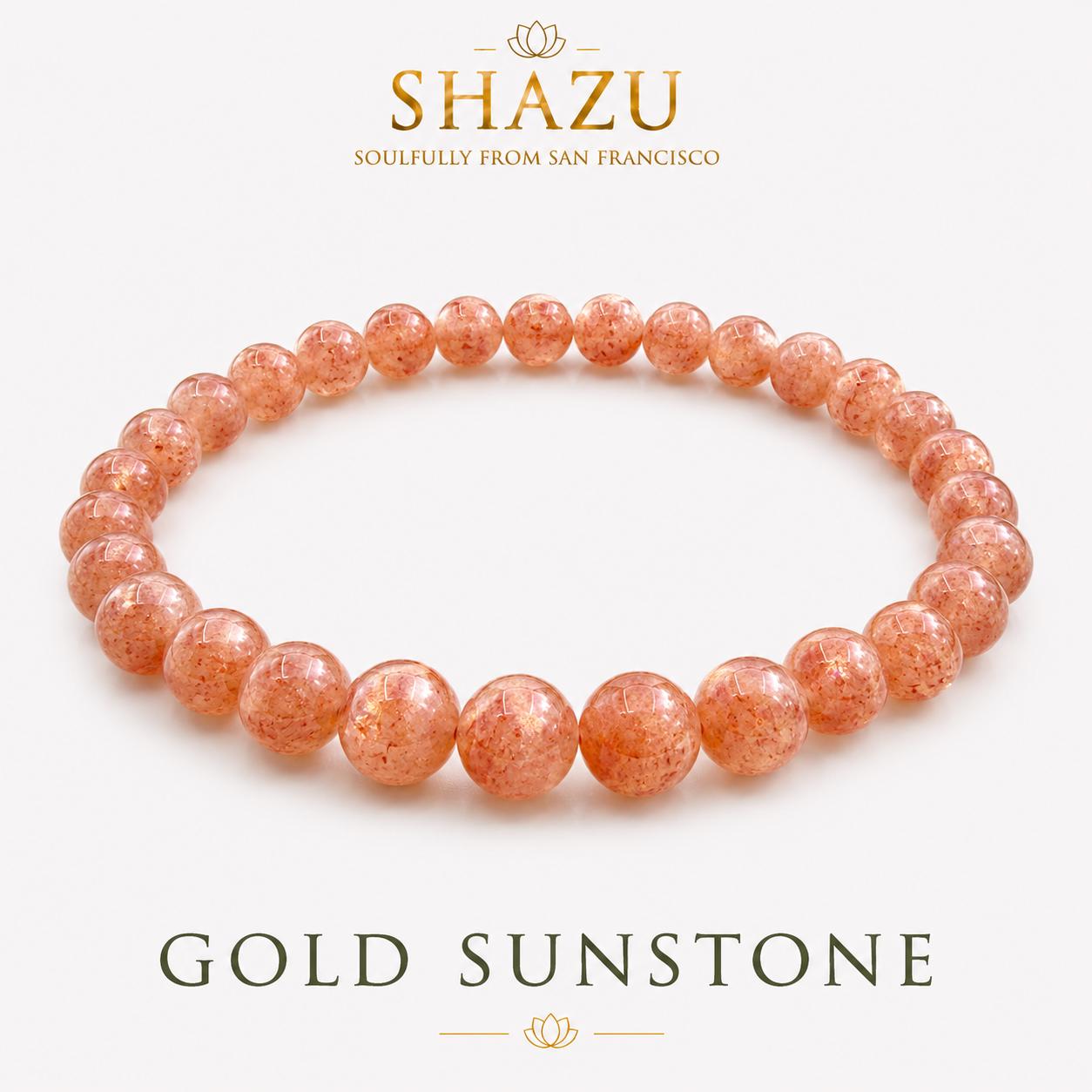 May include: A circular beaded bracelet made of polished, translucent orange-gold sunstone spheres. The text SHAZU SOULFULLY FROM SAN FRANCISCO appears above the bracelet, and the text GOLD SUNSTONE is printed below the jewelry item.