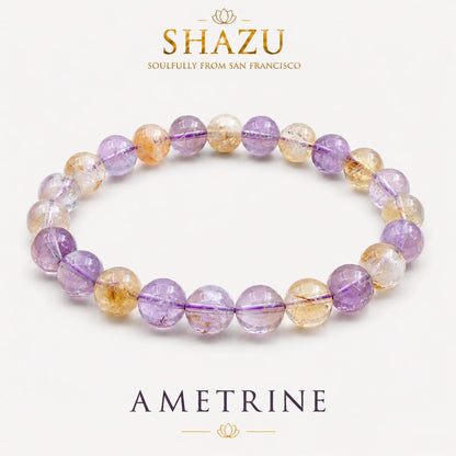 May include: A beaded bracelet featuring alternating round, polished ametrine stones in shades of translucent purple and golden yellow. The text SHAZU SOULFULLY FROM SAN FRANCISCO and AMETRINE appears above and below the jewelry piece.