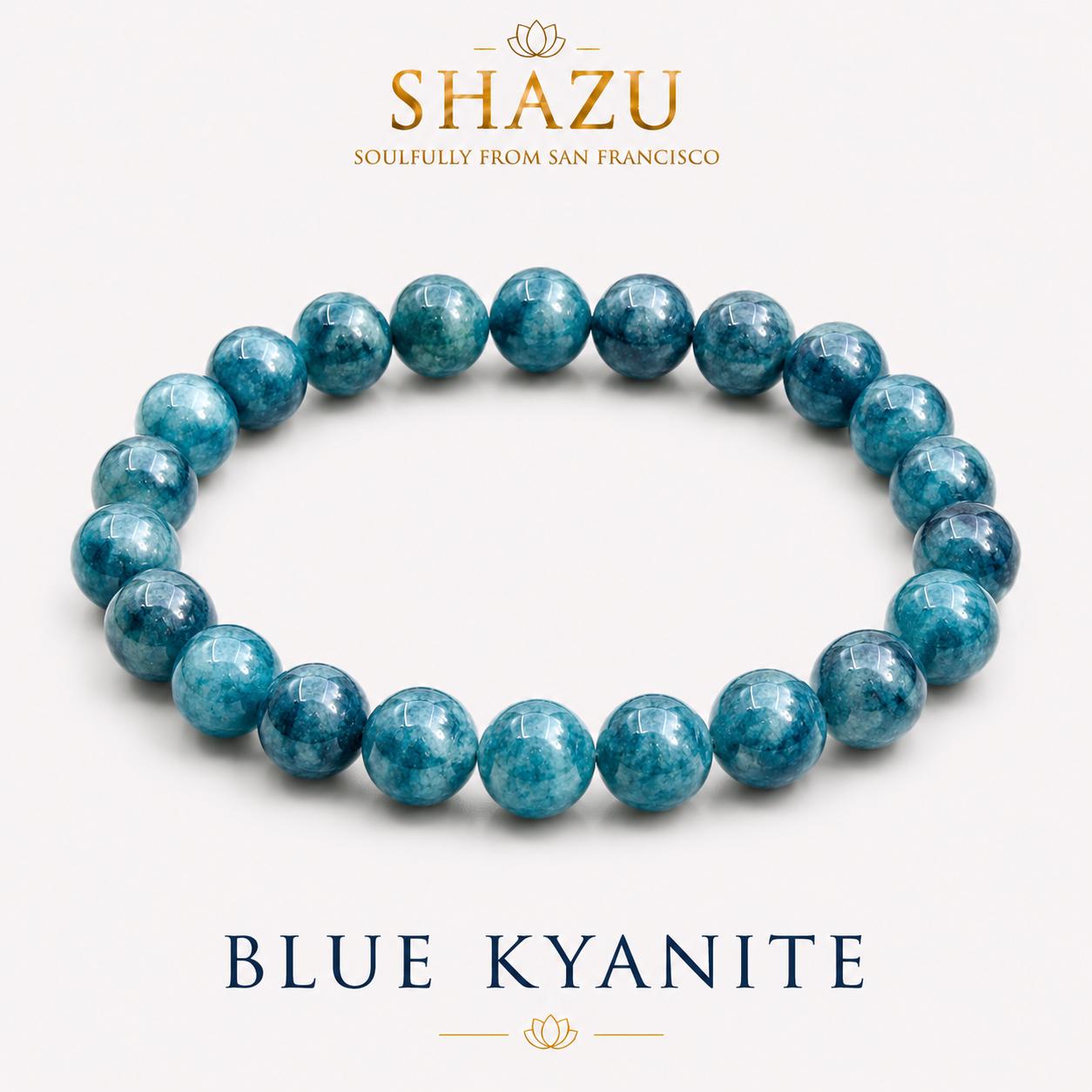 May include: A circular stretch bracelet composed of polished, round blue kyanite beads with varying shades of deep teal and navy. The text SHAZU SOULFULLY FROM SAN FRANCISCO appears above the bracelet, and the text BLUE KYANITE appears below.