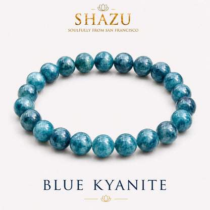 May include: A circular stretch bracelet composed of polished, round blue kyanite beads with varying shades of deep teal and navy. The text SHAZU SOULFULLY FROM SAN FRANCISCO appears above the bracelet, and the text BLUE KYANITE appears below.