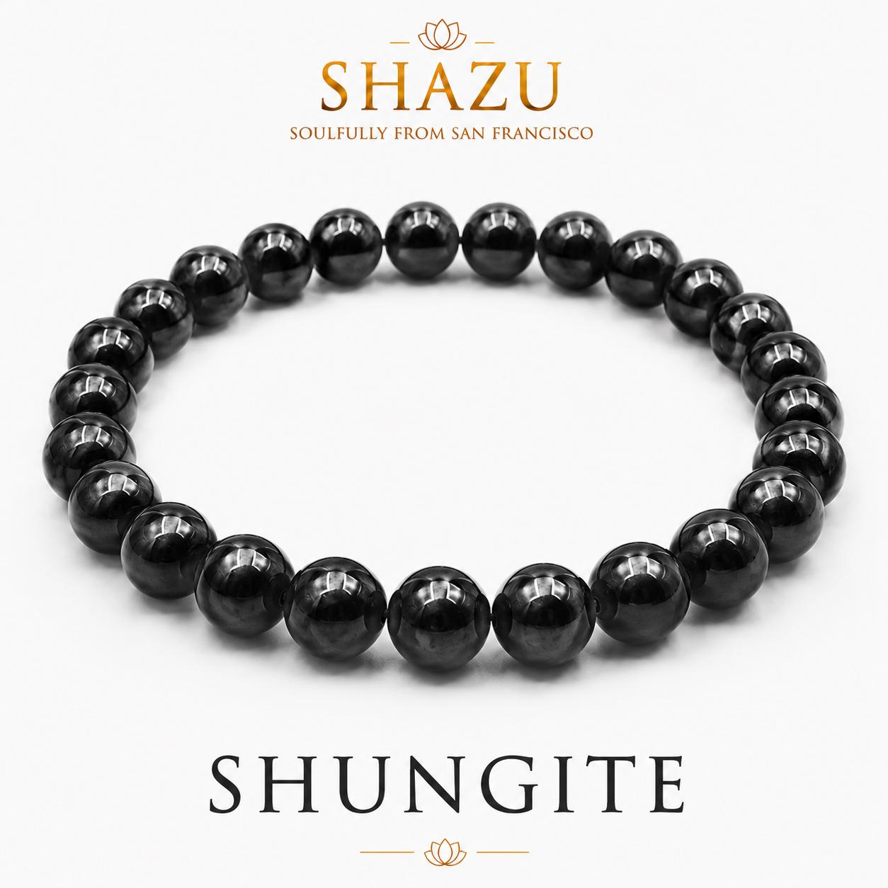 May include: A circular bracelet composed of polished, spherical black shungite beads. The text SHAZU SOULFULLY FROM SAN FRANCISCO appears above the bracelet, and the word SHUNGITE is printed in large capital letters below the jewelry piece.