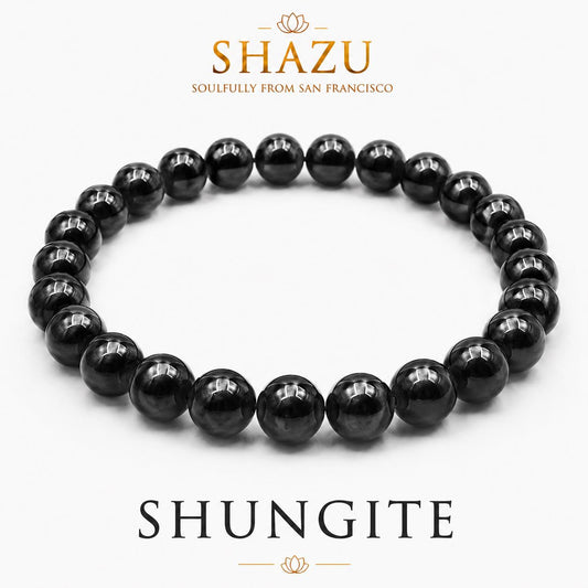May include: A circular bracelet composed of polished, spherical black shungite beads. The text SHAZU SOULFULLY FROM SAN FRANCISCO appears above the bracelet, and the word SHUNGITE is printed in large capital letters below the jewelry piece.