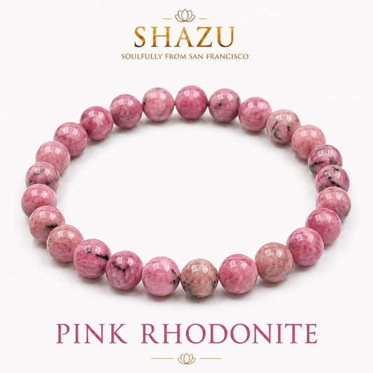 May include: A circular beaded bracelet made of polished pink rhodonite stones with black inclusions. The image includes the text SHAZU SOULFULLY FROM SAN FRANCISCO at the top and PINK RHODONITE at the bottom, centered on a plain white background.