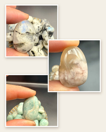A rainbow moonstone, a flower agate and an amazonite tumbled stone, each held in fingertips: the three stones in the Stocking Stuffer Trio